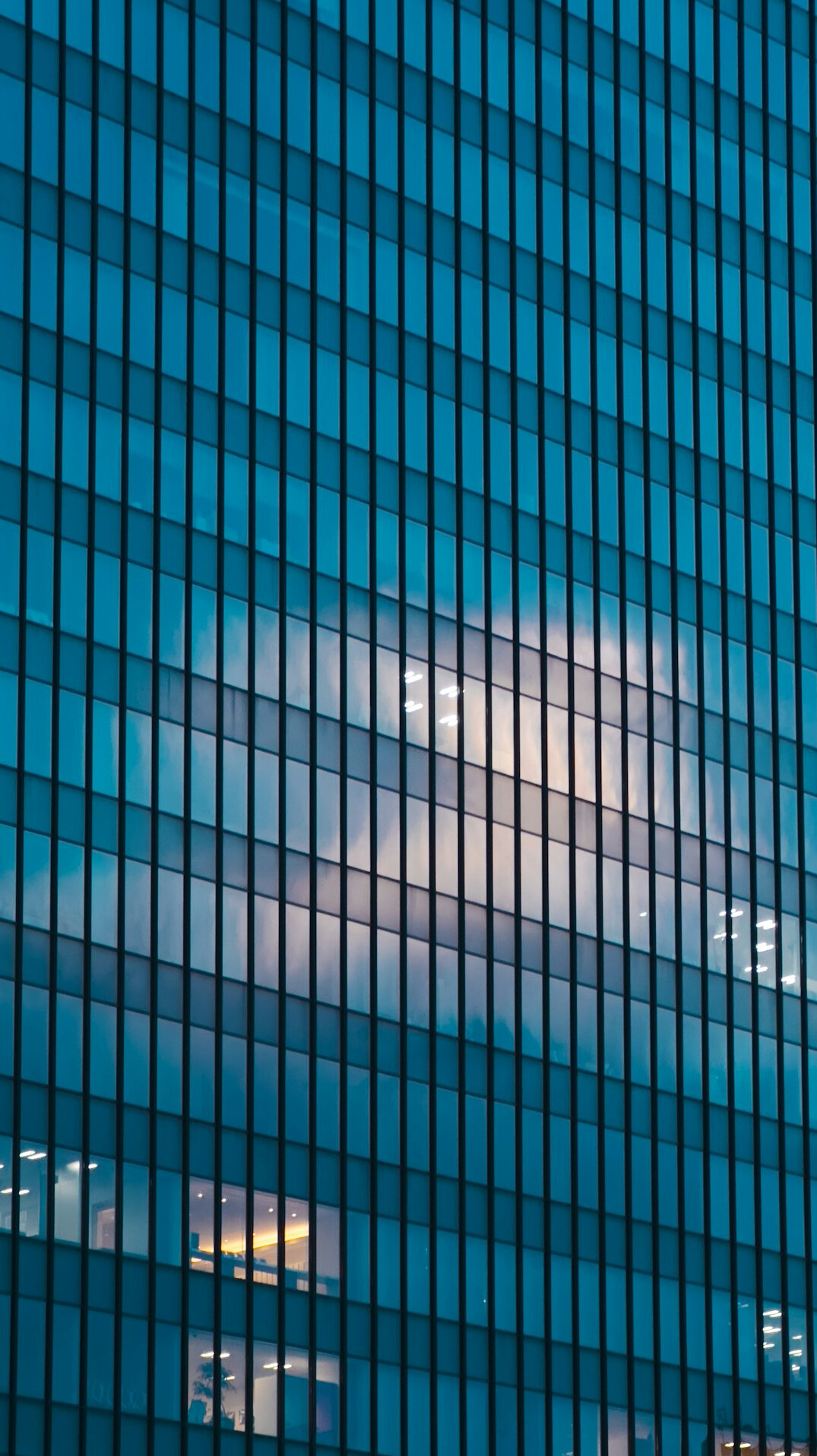 Glass facade of a modern building reflecting the sky